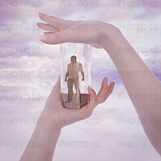 Hands of woman trapping man in glass container