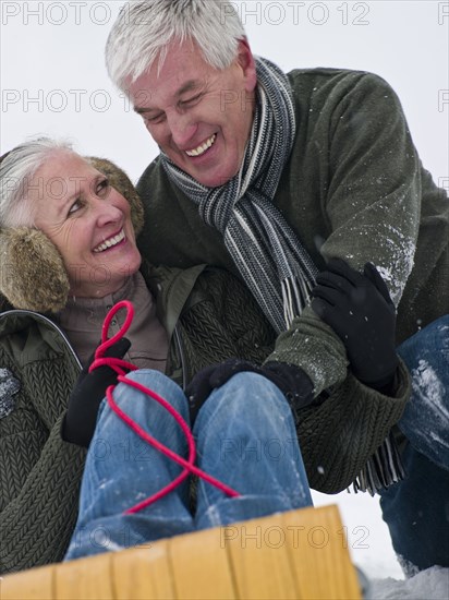 Caucasian couple sledding in snow together