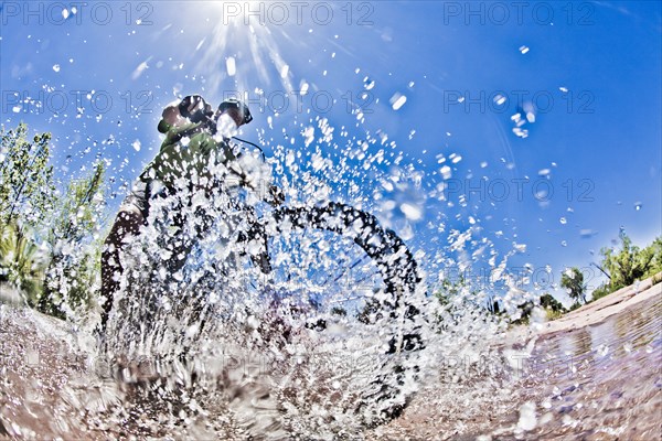 Man riding mountain bike through water