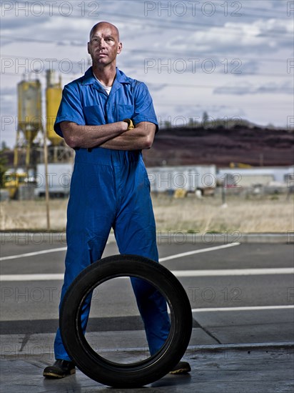 Serious mechanic standing with tire