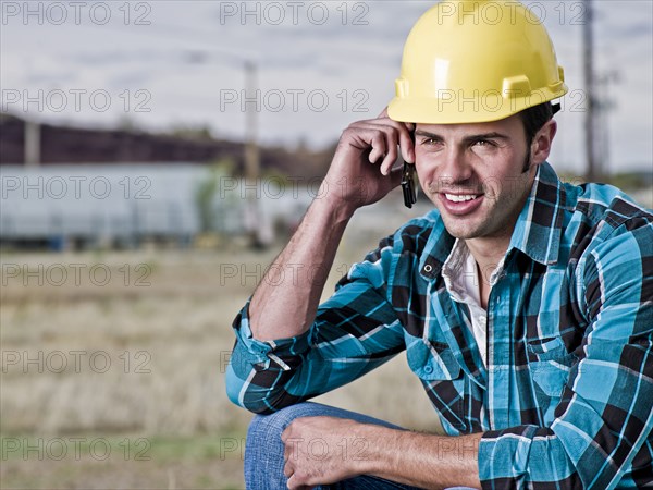 Smiling construction worker talking on cell phone