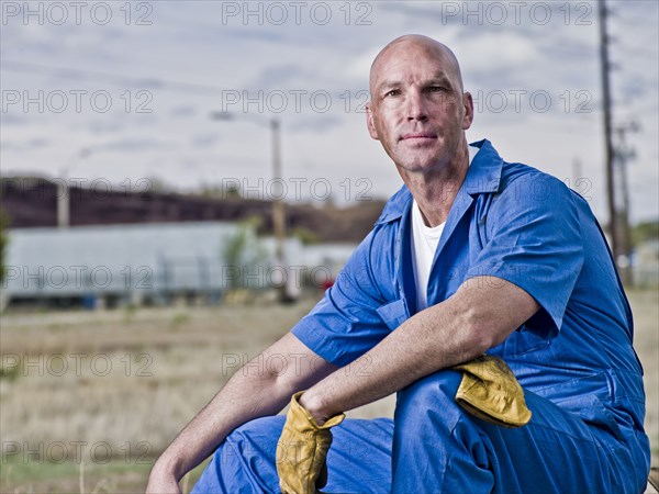 Serious mechanic in coveralls relaxing