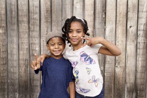 African American brother and sister hugging near wooden fence