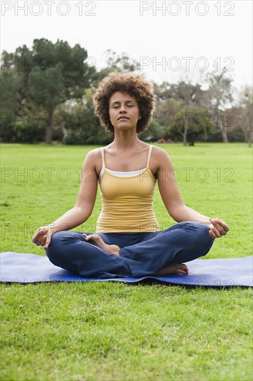 Mixed race woman practicing yoga in park