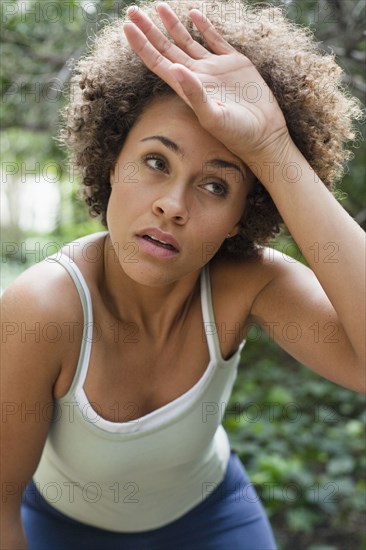 Mixed race woman wiping forehead