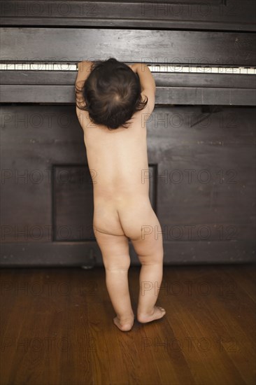 Naked mixed race baby playing piano