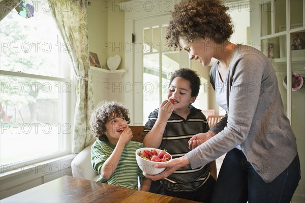 Mother giving sons snack of strawberries