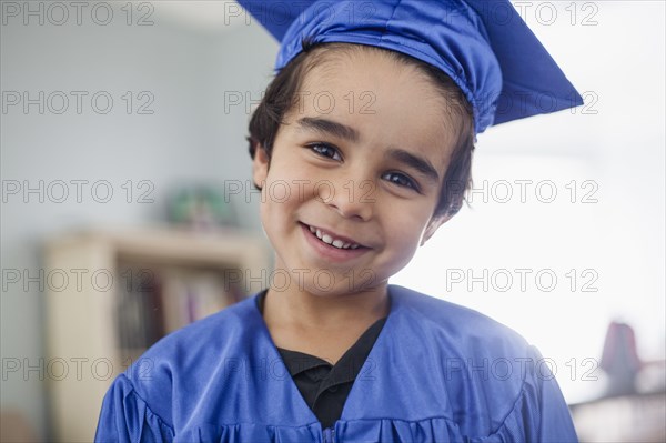 Smiling mixed race boy in graduation cap and gown