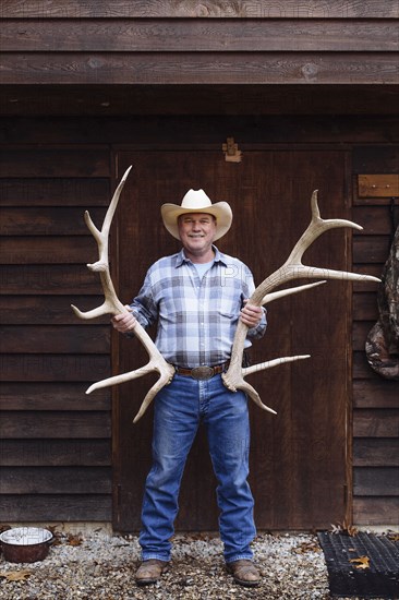 Caucasian farmer holding antlers on front porch