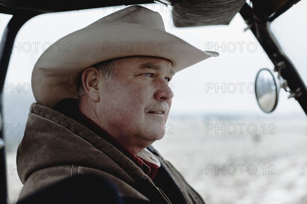 Caucasian farmer driving equipment in farm field