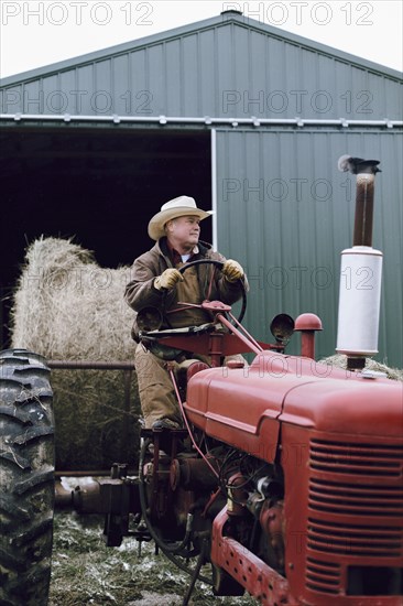 Caucasian farmer driving tractor on farm