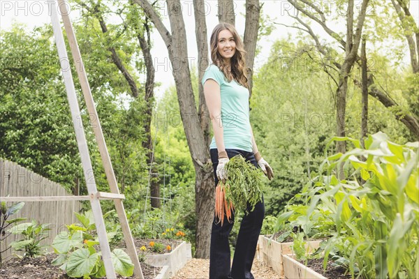 Caucasian woman holding carrots in garden