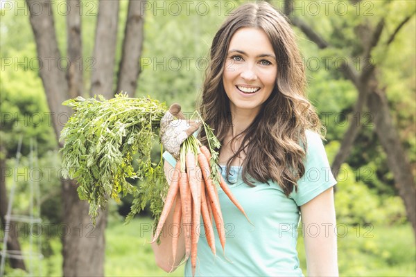 Caucasian woman holding carrots in garden