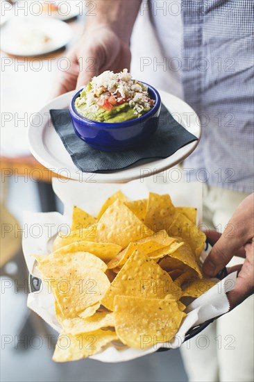 Caucasian man carrying guacamole and tortilla chips