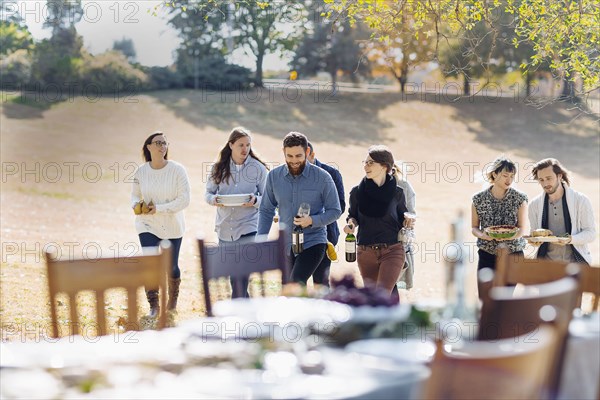 Friends carrying food to outdoor dining table