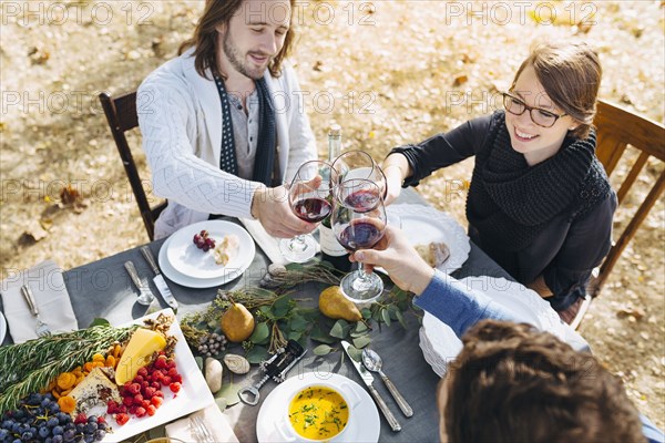 Caucasian friends toasting with wine at outdoor table