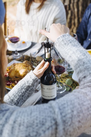 Woman opening bottle of wine outdoors