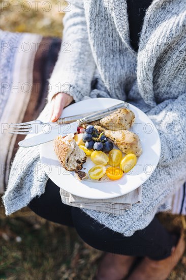 Caucasian woman holding plate of food outdoors