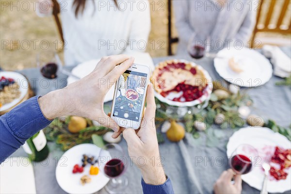 Caucasian man photographing food at outdoor table