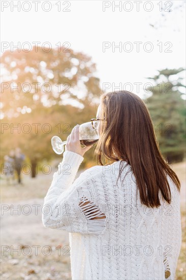 Caucasian woman drinking wine in rural field