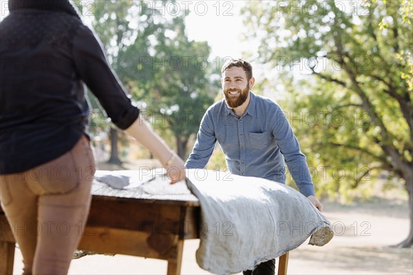 Caucasian couple spreading tablecloth on outdoor table