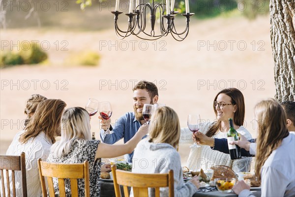 Friends toasting with wine at outdoor table