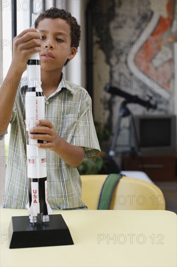 Mixed race boy building model rocket