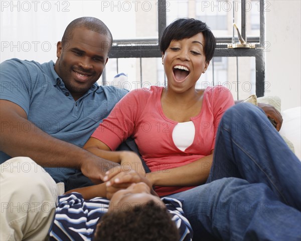 Mother and father tickling son