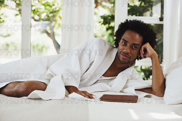 Mixed race man laying on bed reading