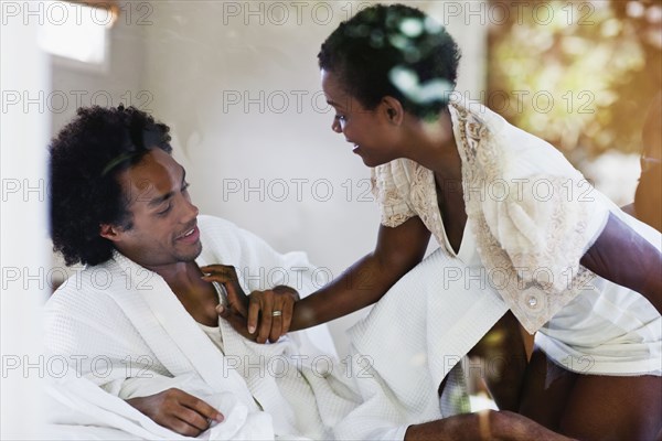 African American woman kneeling on bed with husband