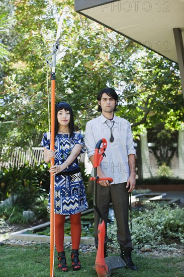 Couple working in garden with tree and weed trimmers