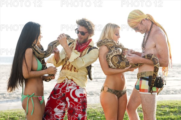 People looking at boa constrictors on beach