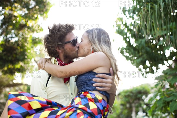 Caucasian man carrying and kissing girlfriend