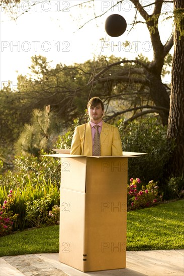 Caucasian man standing in large cardboard box outdoors