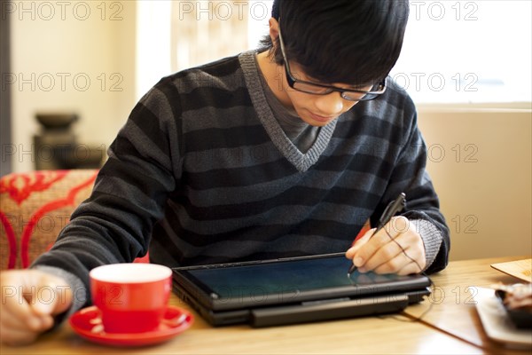 Mixed race man writing on digital tablet