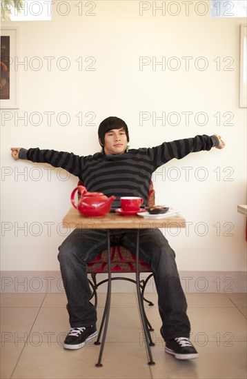 Mixed race man stretching at cafe