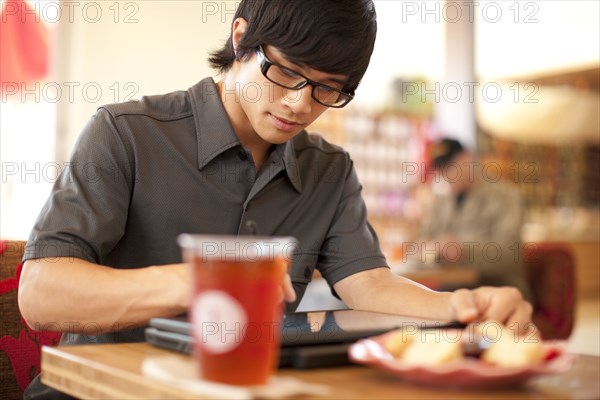 Mixed race man using digital tablet in cafe