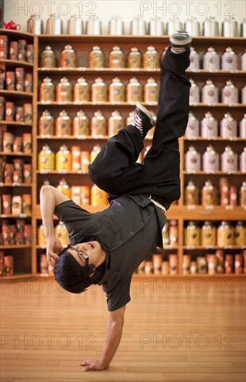 Mixed race man doing handstand in shop