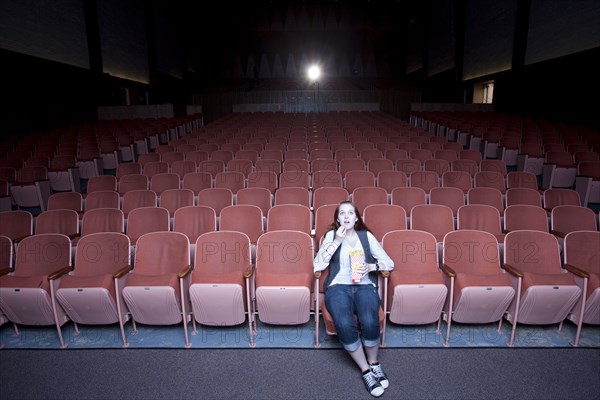 Caucasian woman watching move in empty theater