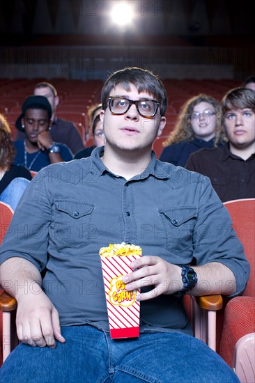 Caucasian man eating popcorn in movie theater