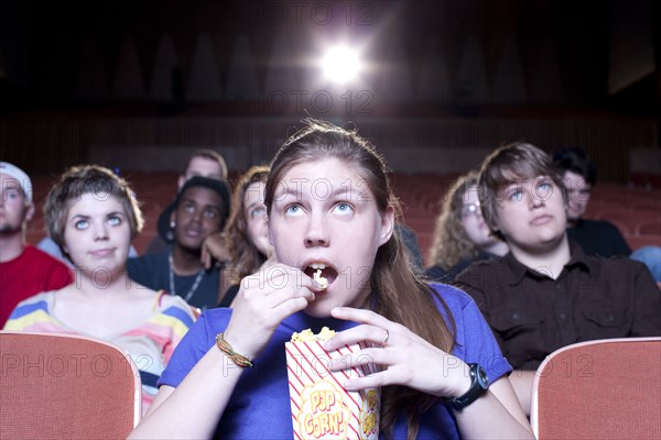 Caucasian woman eating popcorn in movie theater
