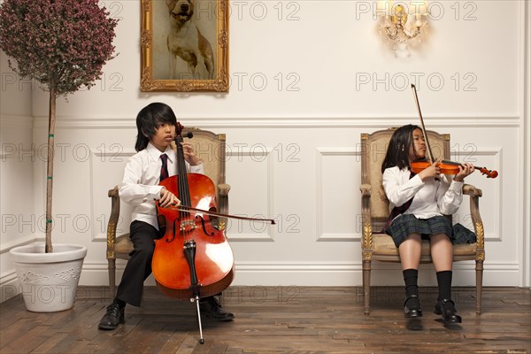 Vietnamese children with musical instruments sitting on elegant chairs