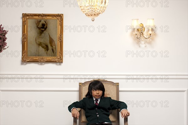 Vietnamese boy sitting on elegant chair