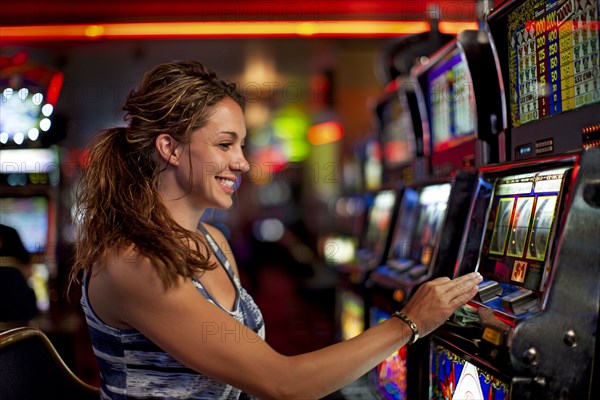 Caucasian woman playing slot machine in casino