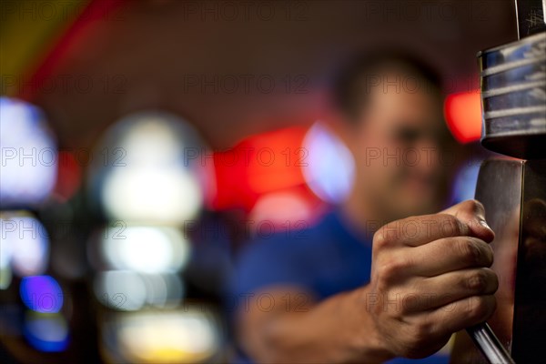 Native American man pulling lever of slot machine in casino