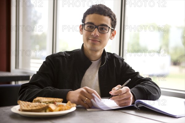 Hispanic student studying in diner and having lunch