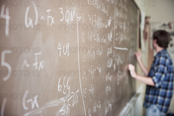 Caucasian student writing on blackboard