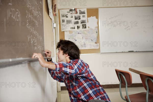 Caucasian student writing on blackboard