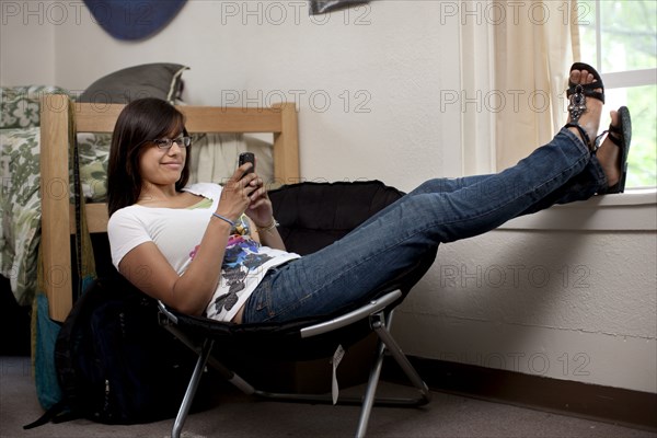 Hispanic woman hanging out in college dorm room