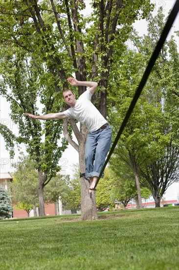 Caucasian man balancing on rope in park